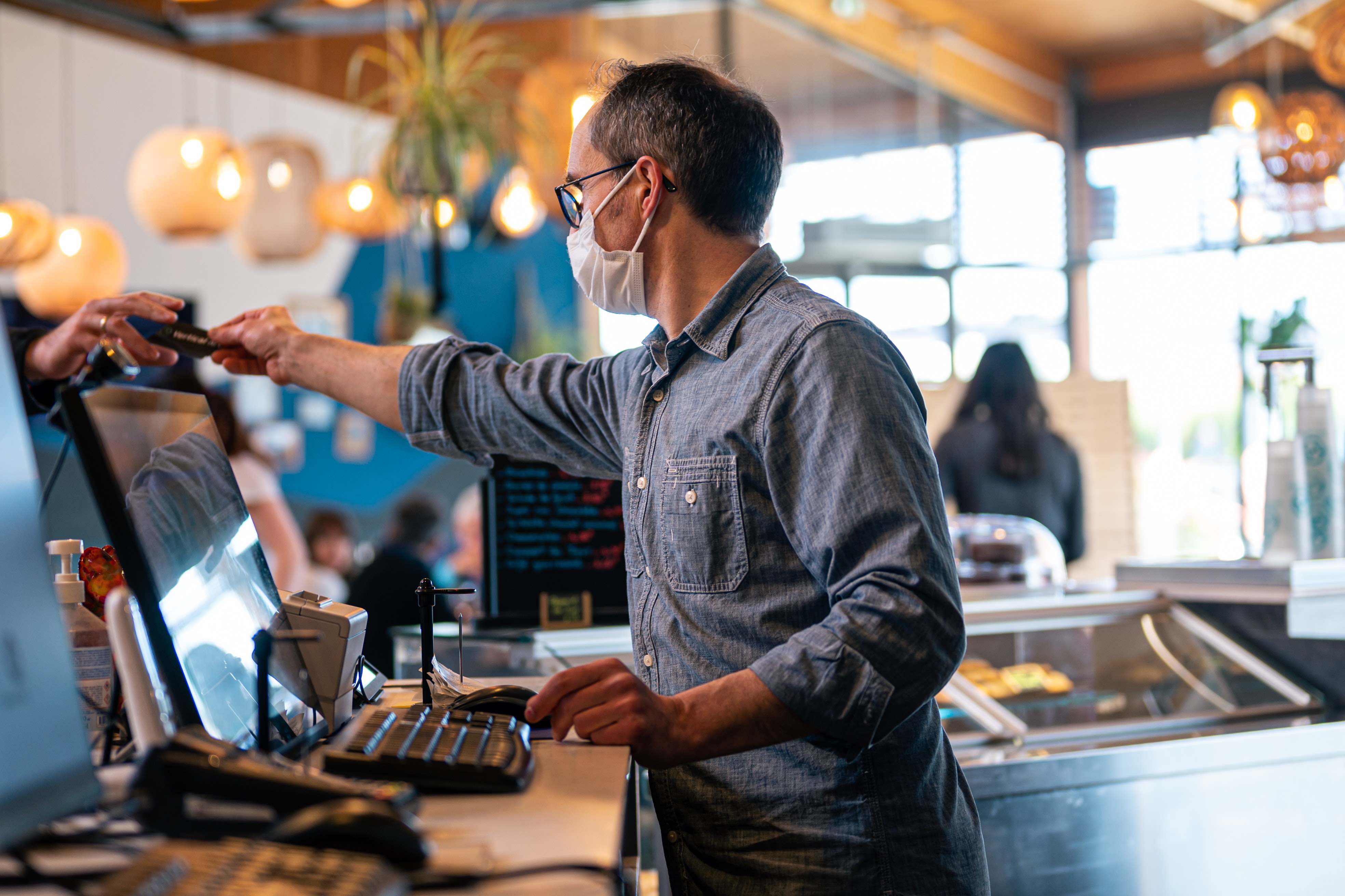 Man working at register utilizing a restaurant labor management platform